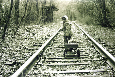 Woman standing on railroad track in forest