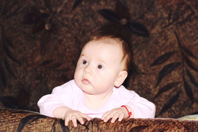 Close-up of cute baby girl relaxing on sofa in darkroom