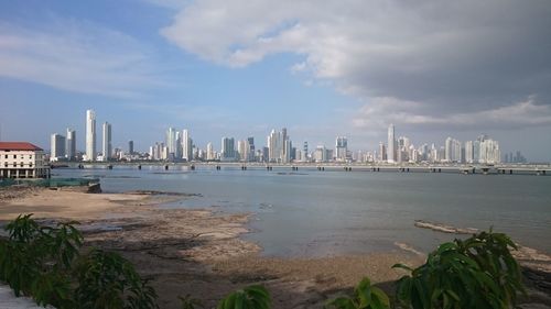 Sea by city buildings against sky