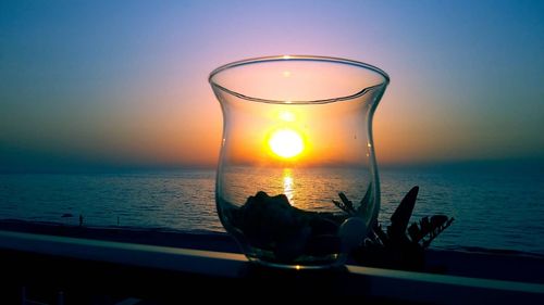View of drink on table against sea during sunset