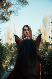 Young woman with horse standing on field against sky
