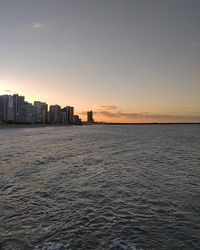 Scenic view of sea and buildings against sky during sunset