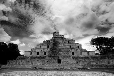 Low angle view of aztec pyramid against cloudy sky