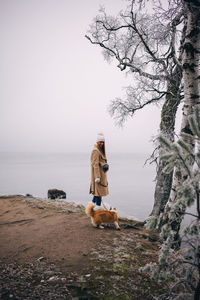 Rear view of woman walking on beach against sky