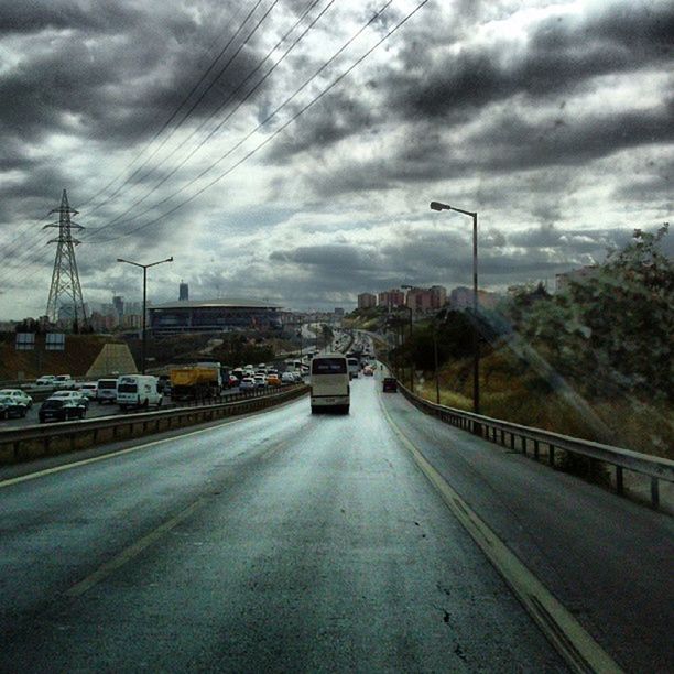 sky, transportation, cloud - sky, the way forward, cloudy, road, car, diminishing perspective, street light, cloud, street, vanishing point, mode of transport, building exterior, built structure, road marking, land vehicle, tree, electricity pylon, architecture