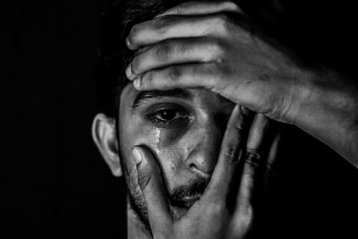 Close-up portrait of man making face over black background