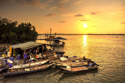 Boats moored in sea against sky during sunset