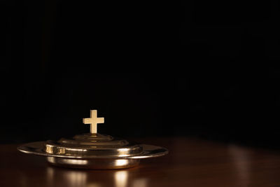 Close-up of illuminated lamp on table against black background