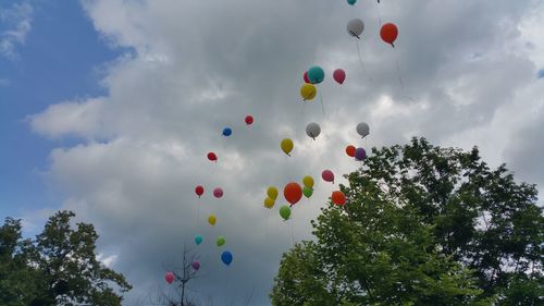 Low angle view of colorful balloons against cloudy sky