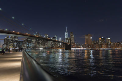 Illuminated bridge over river against sky in city at night