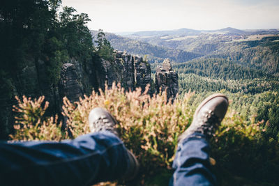 Low section of man relaxing on mountain in forest