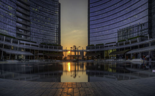 Reflection of buildings in city at sunset