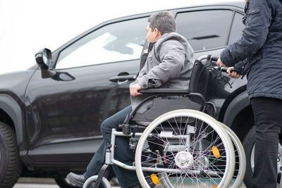 A woman helps aphysical disabled person to get into the car.