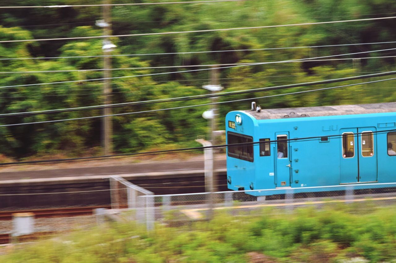 transportation, railroad track, rail transportation, train - vehicle, mode of transport, motion, public transportation, green color, no people, speed, day, blurred motion, focus on foreground, outdoors, on the move, tree, reflection, connection, selective focus, grass