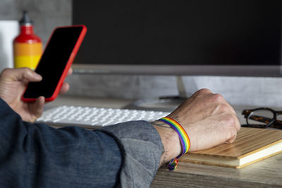 Man's hand working in the office with decoration and lgbt accessories. lgbtqia culture