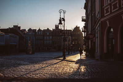 Woman walking on street amidst buildings in city