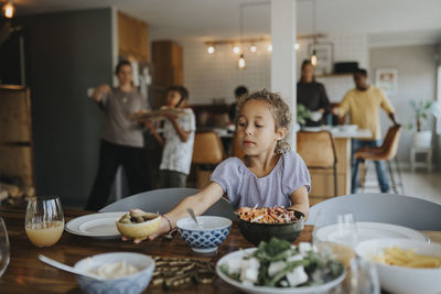 Cute girl keeping bowl on dining table for lunch at home
