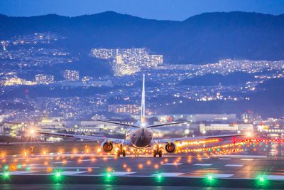 Illuminated airplane on runway against mountains at night