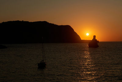 Silhouette boat in sea against sky during sunset