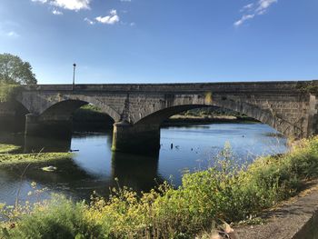Arch bridge over river against sky