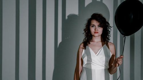 Portrait of young woman standing against wall