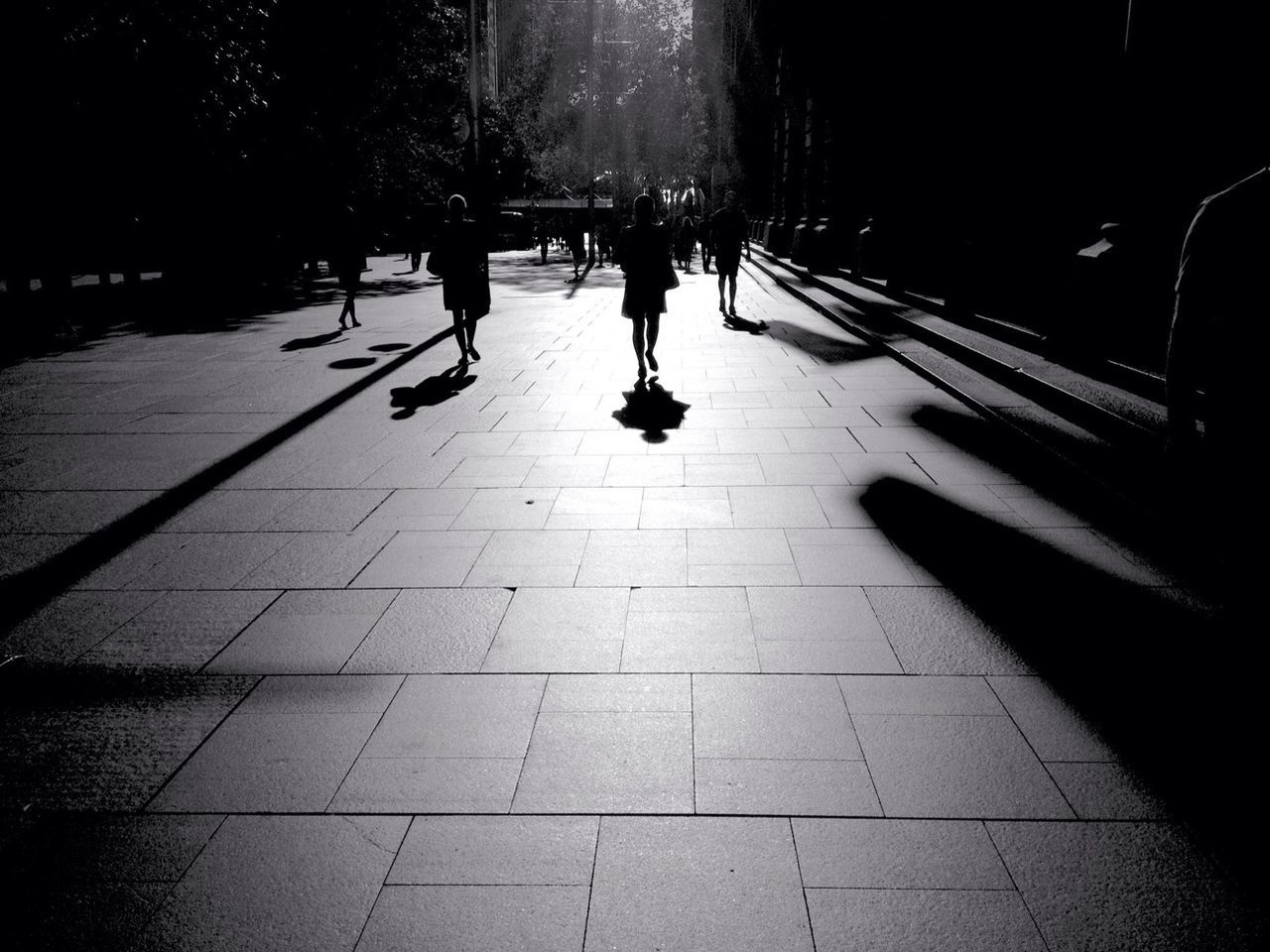 walking, the way forward, street, shadow, built structure, incidental people, men, architecture, city, sunlight, night, transportation, city life, lifestyles, footpath, building exterior, person, cobblestone, unrecognizable person