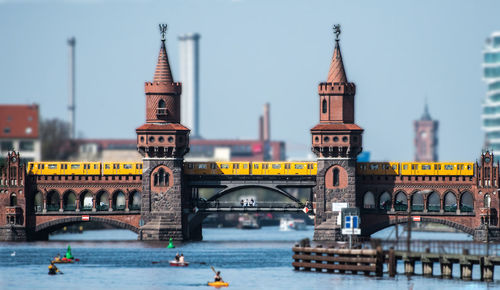 Bridge over river in city against clear sky