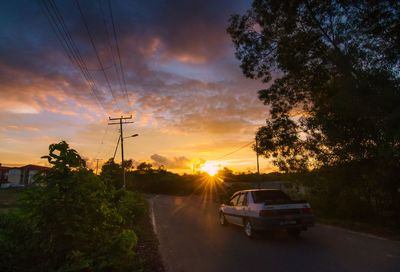 Cars on road against sky during sunset