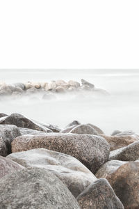 Rocks in sea against clear sky