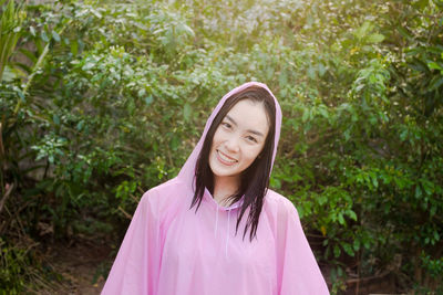 Portrait of smiling young woman with wet hair standing against plants