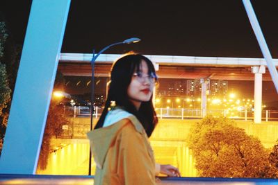 Portrait of woman looking away while standing at night
