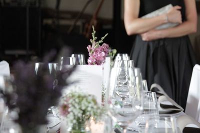 Midsection of woman standing by arranged dining table