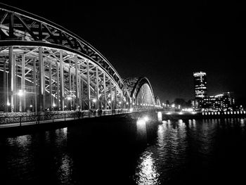 Illuminated bridge over river against sky at night