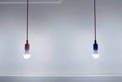 Low angle view of illuminated lamp hanging against sky