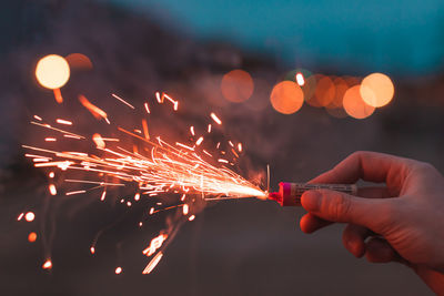 Low angle view of hand holding illuminated firework display