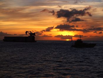 Silhouette boat in sea against orange sky