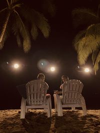 Low angle view of woman sitting on chair at night. beach at night time star gazing