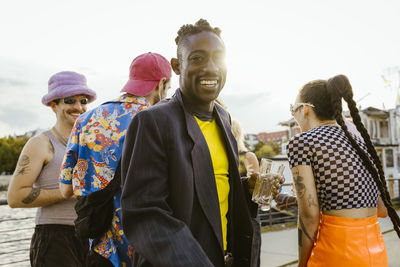 Portrait of happy non-binary person with friends having fun in background