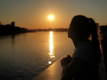 Silhouette woman on shore against sky during sunset