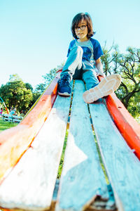 Low angle view of woman sitting on playground against sky