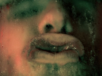 Cropped lips of man seen through wet glass