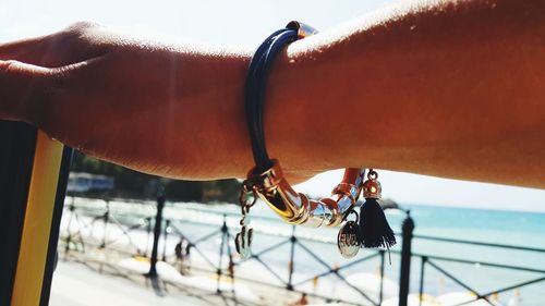 Cropped hand wearing bracelet against sea