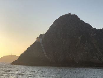 Rock formations by sea against clear sky