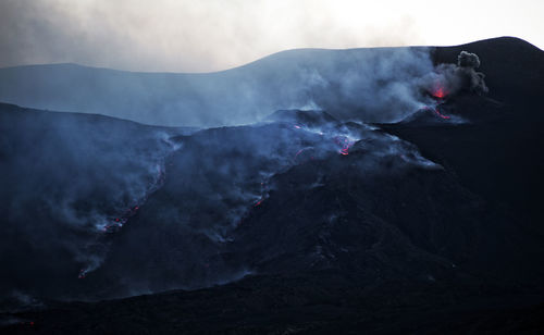 Smoke emitting from volcanic mountain against sky