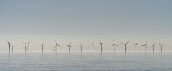 Offshore wind turbines generating renewable electricity and energy  atmospheric background image