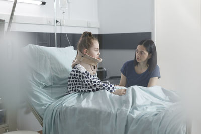 Woman talking to daughter with neck brace at hospital