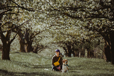 Woman sitting with dog on land at park