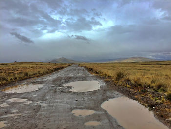 Surface level of road amidst field against sky