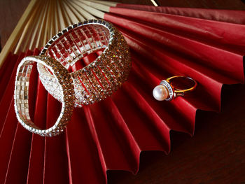 Close-up of jewelry on red hand fan at table