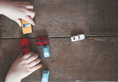 Cropped hands of person playing with toy cars on table